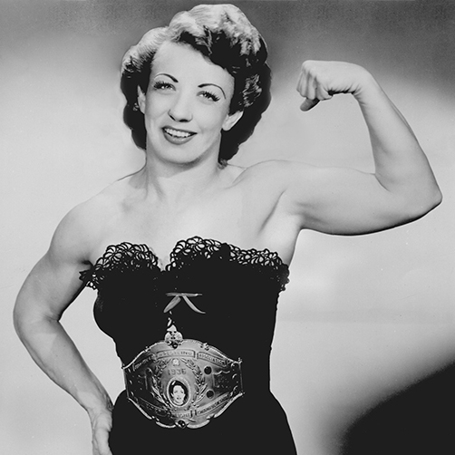 A smiling woman poses and flexes her bicep muscles