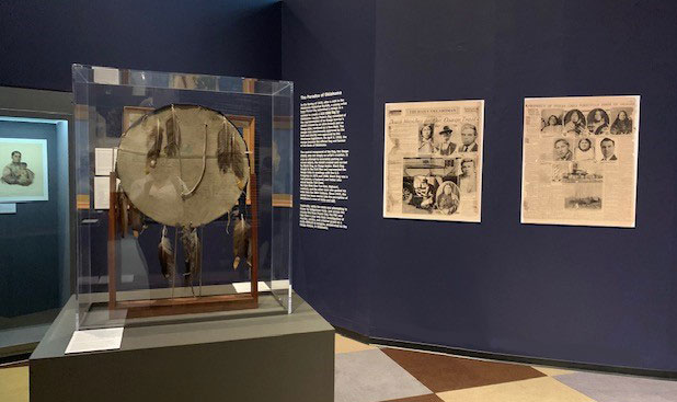 The exhibit features an historic Osage shield, images of newspaper articles, and other artifacts.