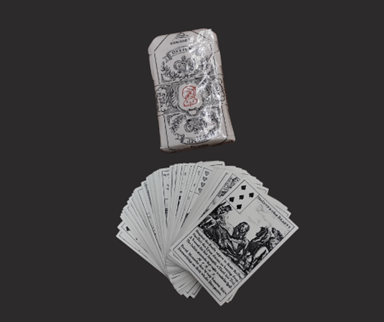 A deck of ornate playing cards fanned out next to the box.