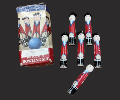 Small wooden pins painted to resemble British soldiers next to a box labeled Wooden Bowling Set.