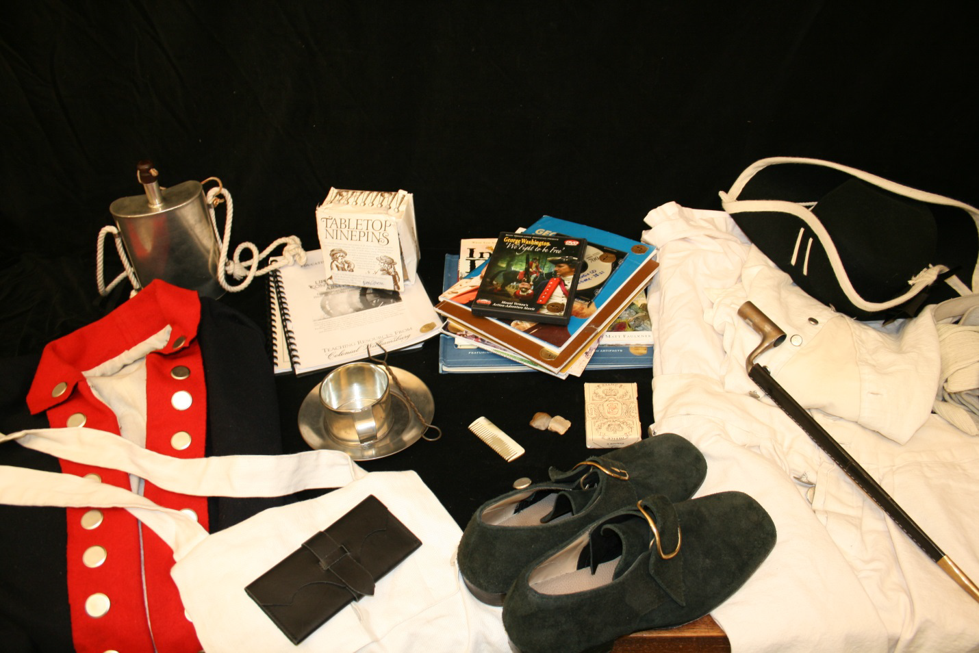 A uniform, shoes, books, and a metal cup and saucer included in the trunk.