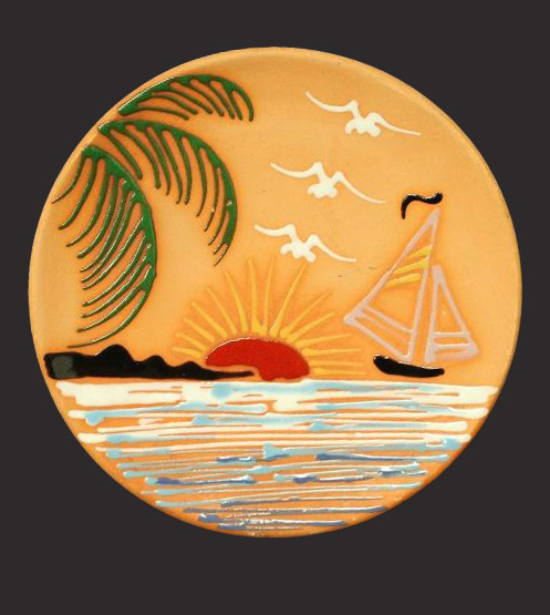 A plate with a sunset over a small land form and water. The design includes a sailboat, birds, and fronds.
