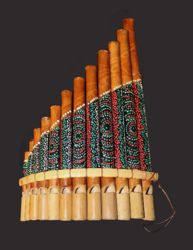 A wooden panpipe with a design featuring concentric circles created by small dots.