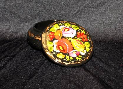 A small round container with large flowers painted on the lid.