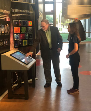 A man demonstrates a touchscreen to a young woman