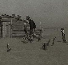 A man and two children run towards a house during a dust storm