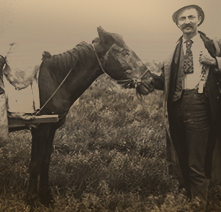 Land seeker Lew Carrol poses next to a horse packed with buckets and other items