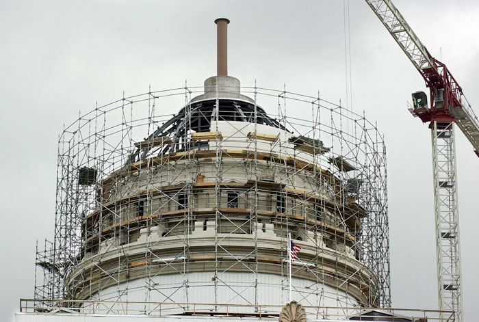 The framework of a dome under construction. Metal scaffolding surrounds the entire structure and a crane is nearby. 
