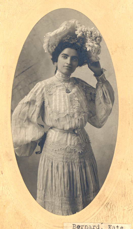 A portait of Kate Barnard in a formal dress wearing an ornate hat.