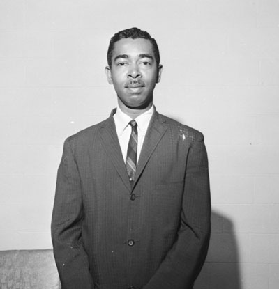 E. Melvin Porter stands looking straight ahead and smiling. He is wearing a suit and tie.