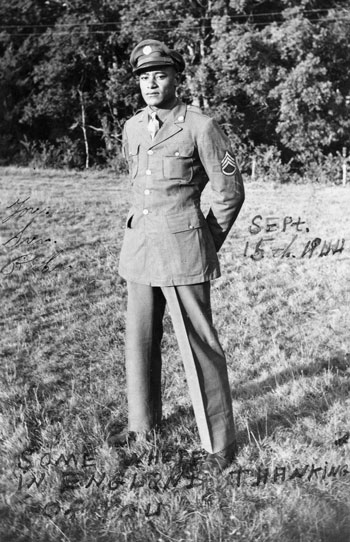 A young Black man stands outside wearing a military dress uniform.