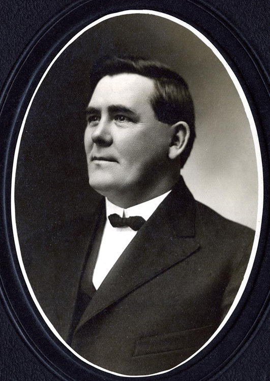 A historic photographic portrait of Peter Hanraty, a white man wearing a dark suit and bow tie. 