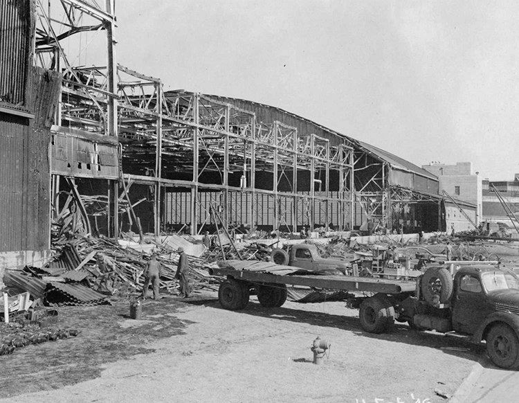 A large building in the process of being constructed. A large flatbed truck is in the foreground. 
