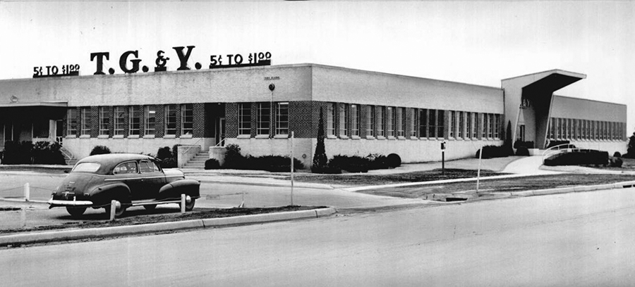 A large building with a sign that says, 'five cents to one dollar, TG&Y. A vehicle is parked outside. 