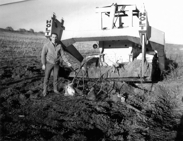 A man stands next to a bulldozer in a field.