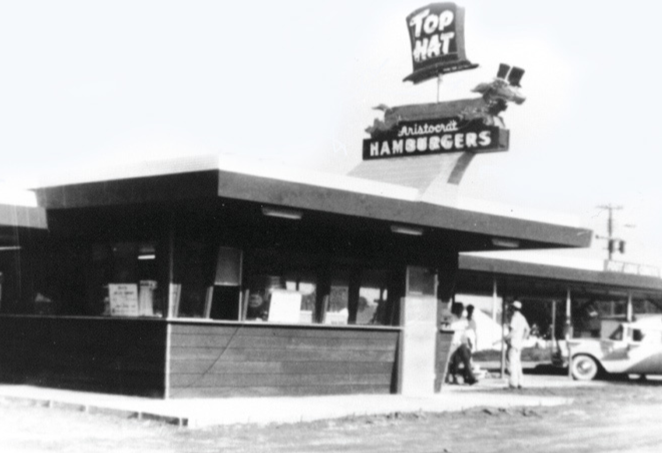 A small building with a sign that reads, 'Top Hat, Aristocrat Hamburgers.'