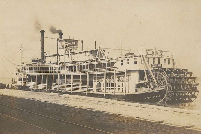 Historic photograph of a large steamboat with smoke coming out of smokestack. 