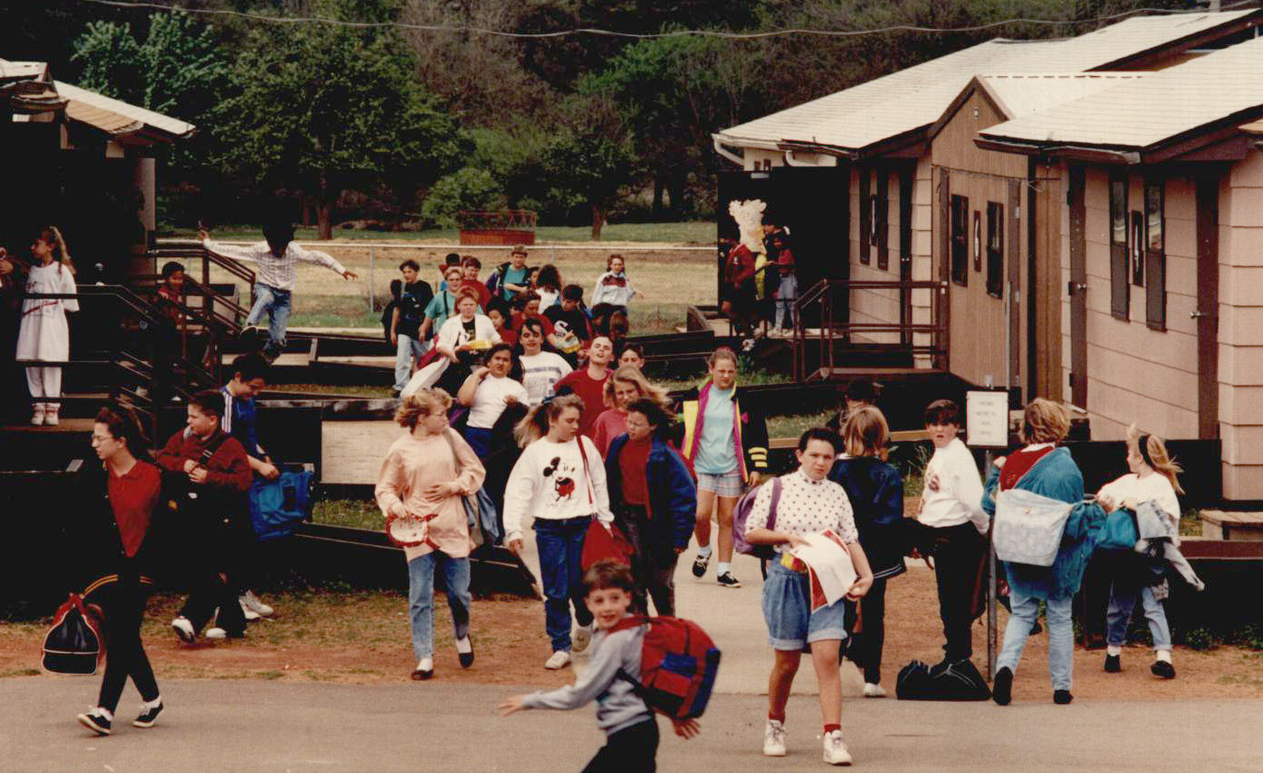 Students walking to and from portable buildings carrying backpacks.