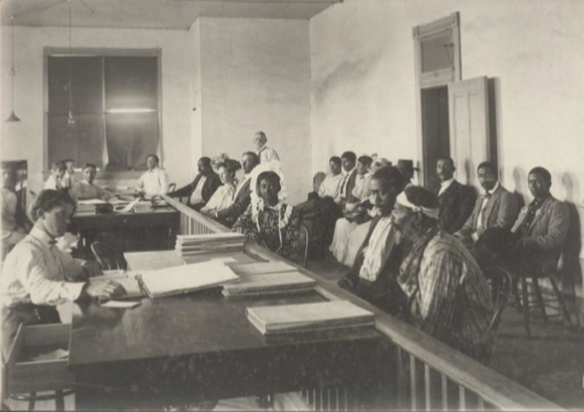 Freedmen men and women seated across from workers at desks