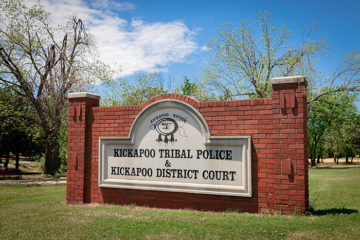 A brick sign in a green field showing the Kickapoo tribal seal. In larger letters below, it reads Kickapoo Tribal Police and Kickapoo Tribal District Court. 