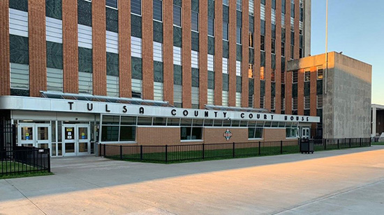 Building with a sign reading Tulsa County Court House. The multi-story building has brown brick and white metal exterior features.