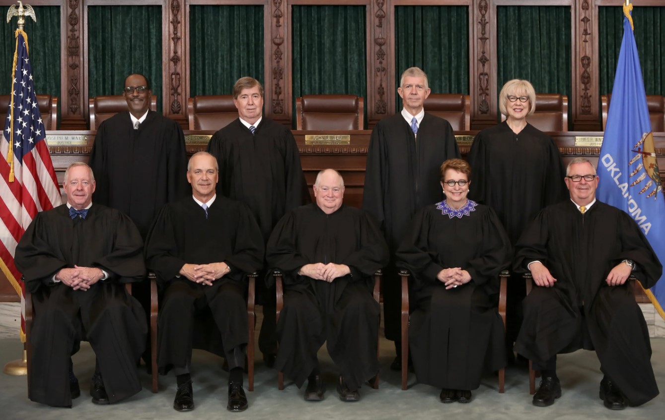 Two women and seven men posed in their judge's robes in front of the US and Oklahoma flags.