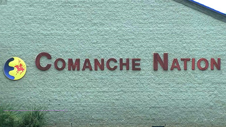 A gray brick building with the Comanche Nation seal and the words Comanche Nation on the exterior. 