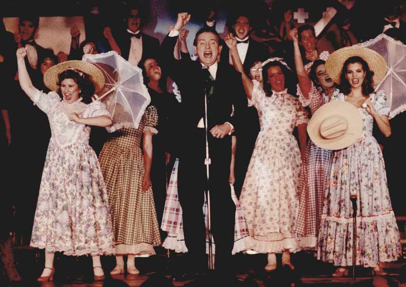 A crowd of actors and the ensemble, including Ridge Bond (center) enthusiastically belt out ‘Oklahoma!’  
