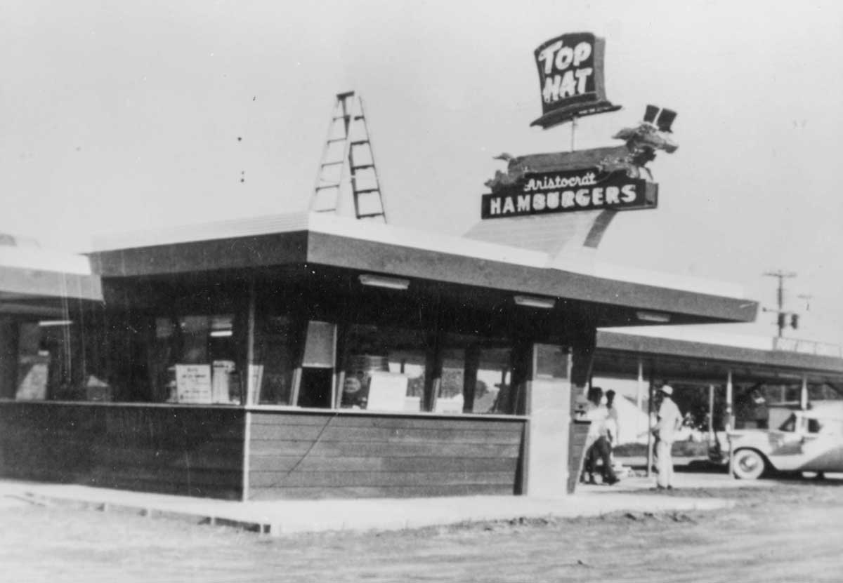 A few people walking into a small Top Hat restaurant