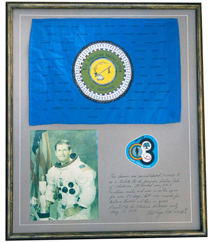 A framed piece including a flag, portrait of Pogue, and Skylab 4 mission patch.