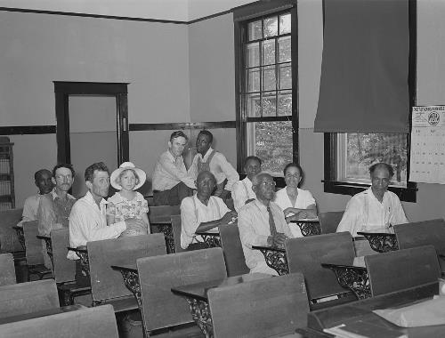 A group of people, both Black and white, in a room at a meeting.