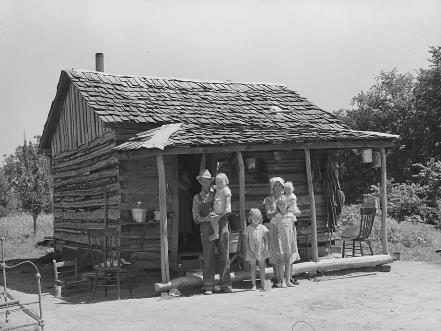 A white family of six stands in front of a small cabin