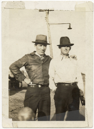 Two white men in hats pose for a photograph. 