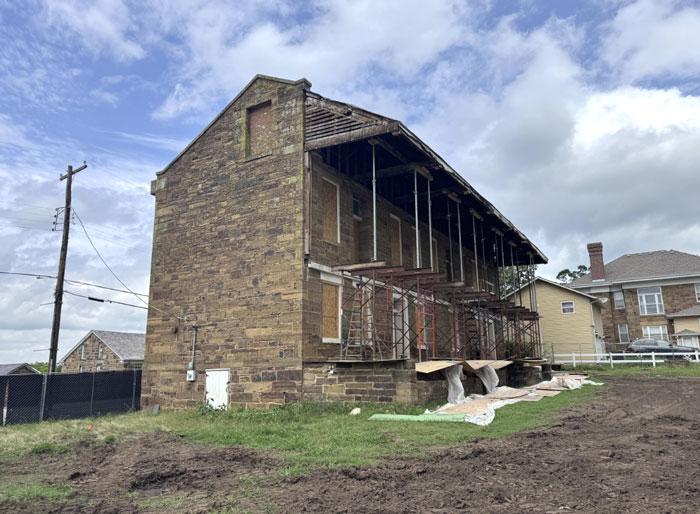View of the stone barracks from the side, showing scaffolding and covering where windows were removed.