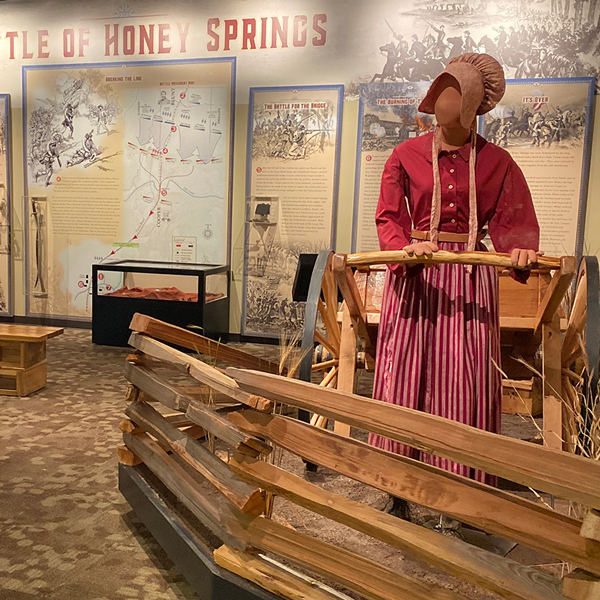 Female mannequin in period pioneer dress pulls a wooden cart