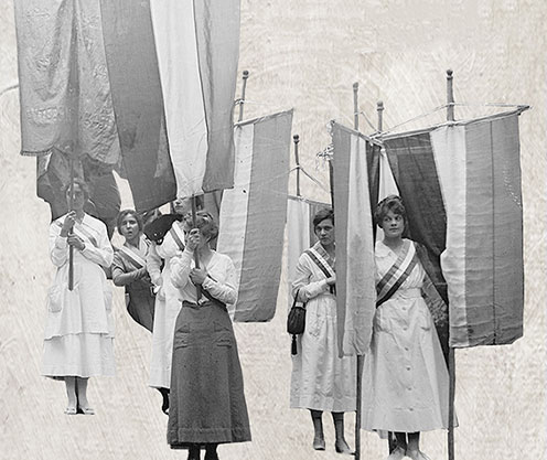 Women protesting for suffrage hold large fabric banners.