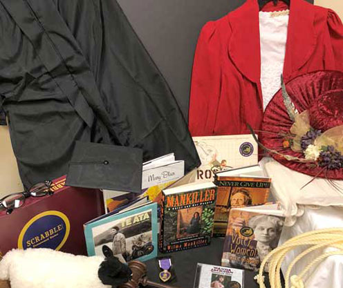 Books, a Scrabble game, and women's clothing are part of the traveling trunk.